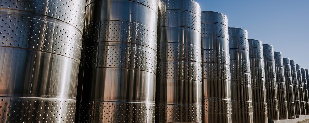 Steel modern cisterns for wine production on plant territory. Large tanks Steel modern cisterns for wine production on plant territory. Large tanks, barrels on winery factory. High quality photo